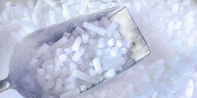 Metal scoop filled with dry ice pellets on a bed of dry ice.