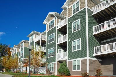 A row of green apartment buildings under a clear blue sky.