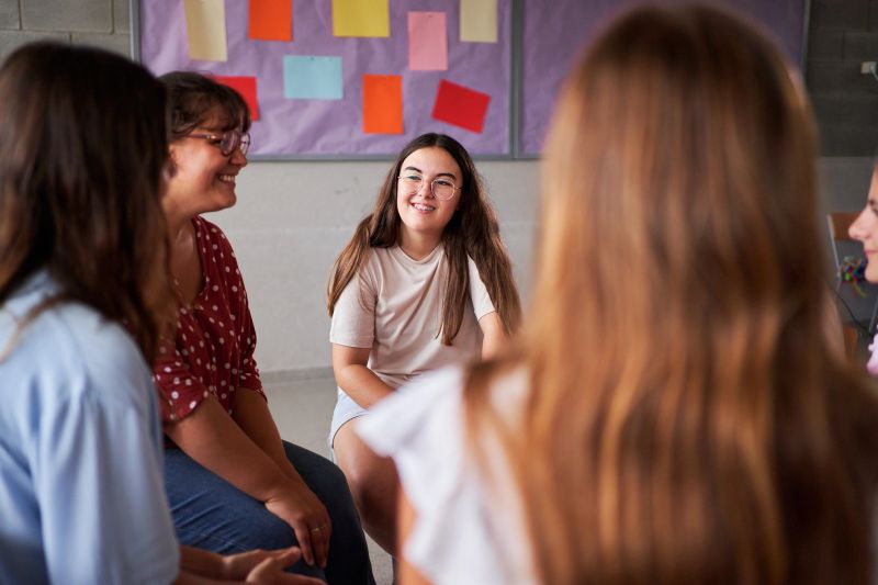 Teenage girls are participating in a support group meeting at school, sharing their experiences and providing mutual support. Image with copy space.