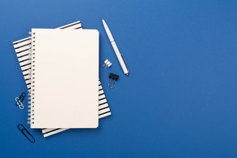 Notebook with stationary on color background, top view