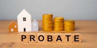 Wooden blocks spelling 'PROBATE' with house models and coin stacks in the background.