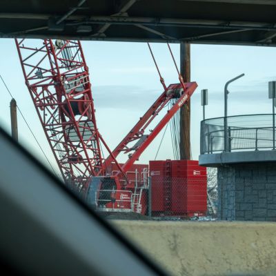 Red construction crane behind roadside barrier.