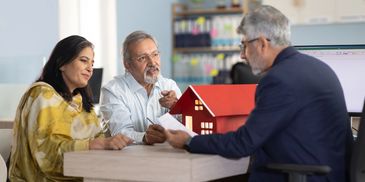 Couple discussing home purchase with a real estate agent in an office.