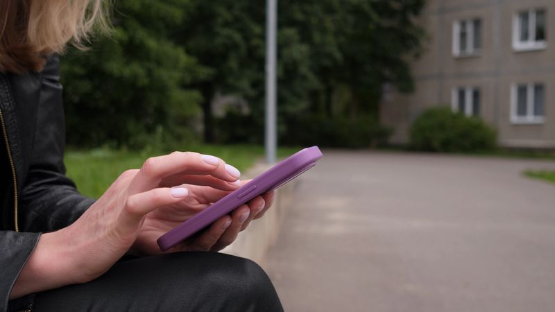 In a peaceful and serene outdoor setting, a young woman fully engages and interacts with her smartphone device