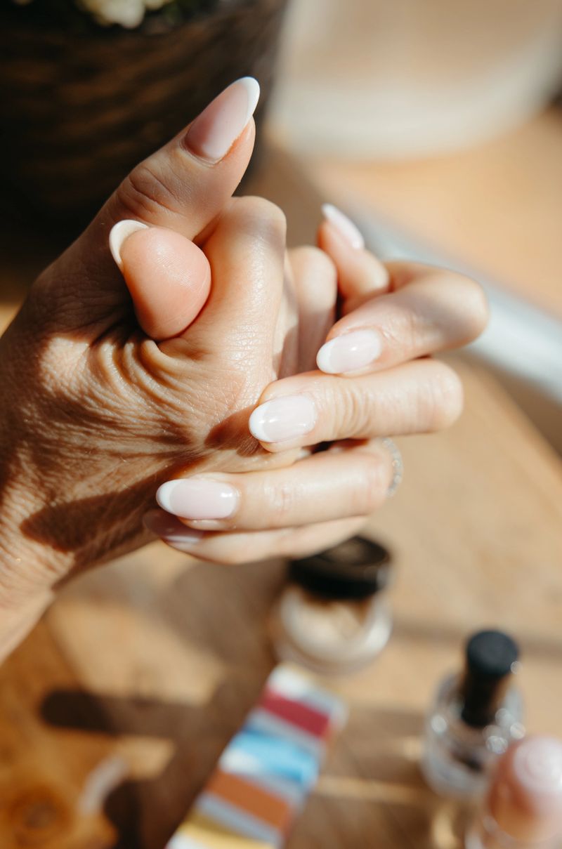 Detail of female hands with manicured nails in soft natural light on a wooden table