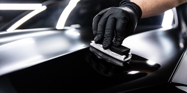 Person polishing a black car surface.