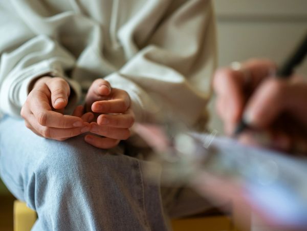Person nervously folding hands in therapy session.