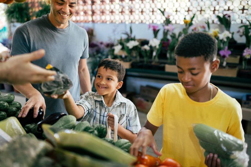 Young boys choosing organic vegetables with their father at the local farmer's market