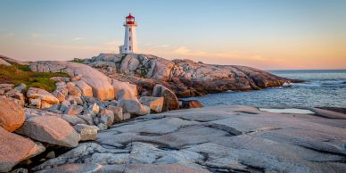 A lighthouse on rocky coastline at sunset.