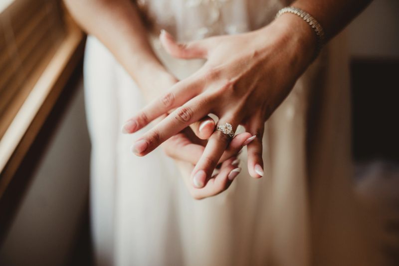 Bride getting ready for wedding ceremony sliding on wedding ring