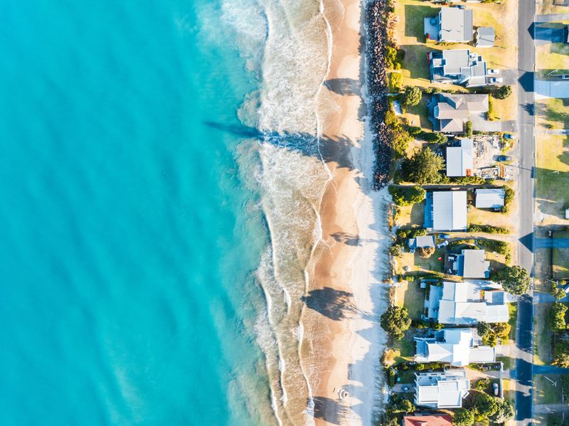 Vista panorâmica da praia em Torres, destacando casas e terrenos disponíveis.