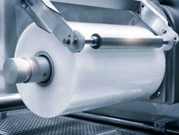 Close-up of a large industrial roll of plastic film on a machine.