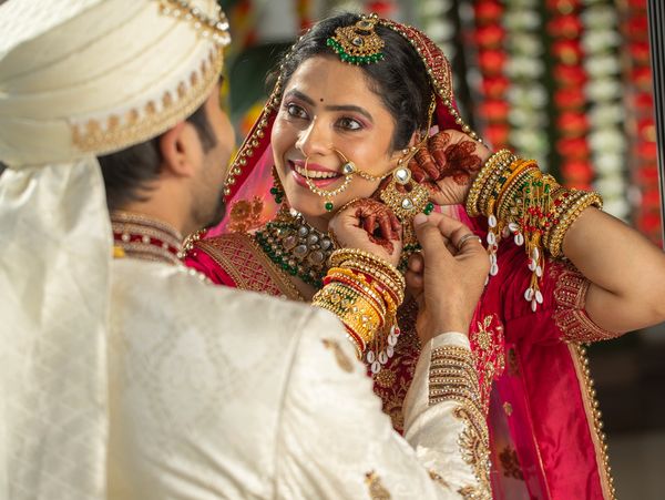 Bride and groom in traditional Indian wedding attire sharing a joyful moment.
