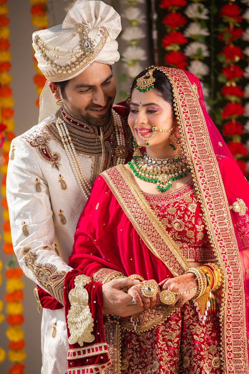 Portrait of beautiful bride and handsome groom in traditional clothing holding hands and standing together at wedding ceremony