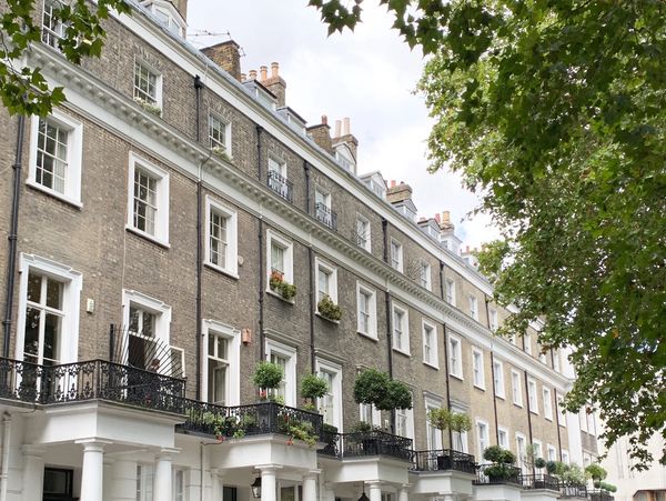 Elegant row of townhouses with white columns and greenery on balconies.