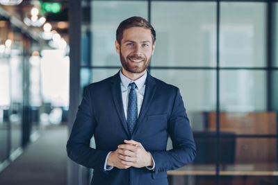 Confident businessman in a suit smiling in a modern office.