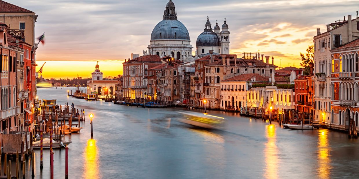 Sunset over Venice's Grand Canal with historic buildings and domes.