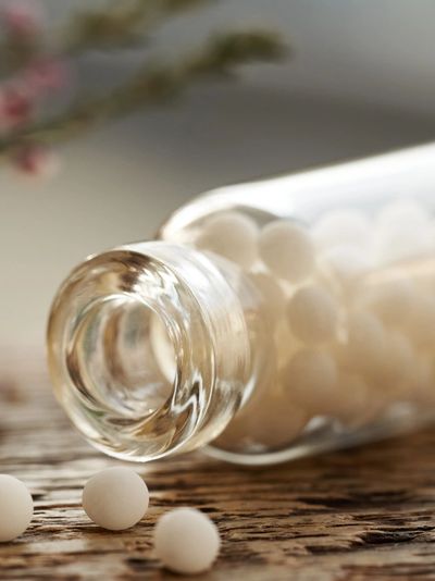 Glass bottle tipped over with white round pills spilled out.