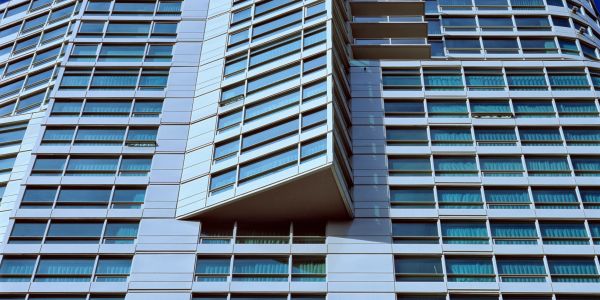 Close-up of modern glass and metal building facade with an overhanging section.