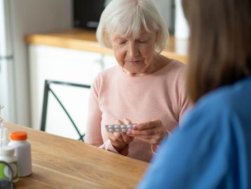 A woman helping a senior with sorting out her medications.