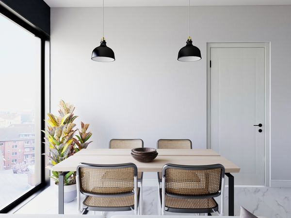 Minimalist dining area with natural light and rattan chairs.