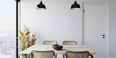 Minimalist dining area with a wooden table, four chairs, and two black pendant lights.