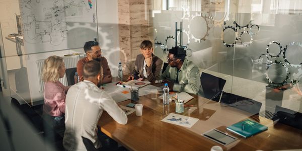 A diverse team engaged in a collaborative meeting around a table in a modern office.