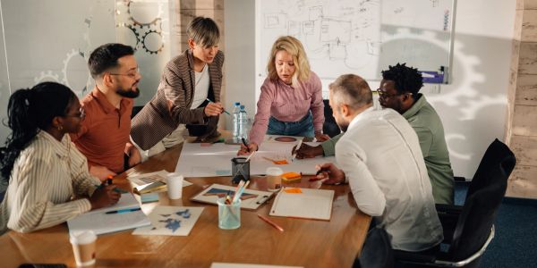 A diverse team collaborating around a table with documents and notes.