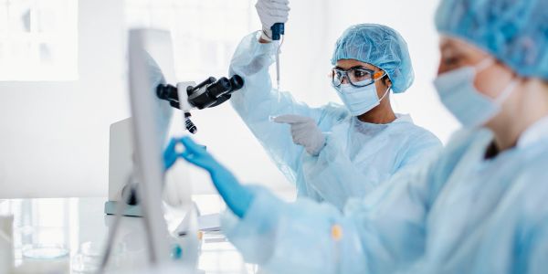 Scientists in protective gear work in a lab using advanced equipment.