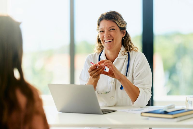 Happy female medical expert communicating with her patient during an appointment at doctor's office.