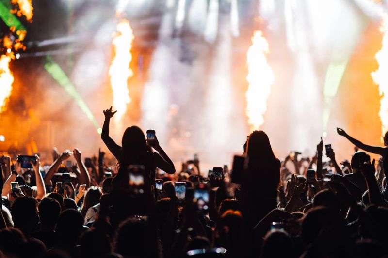 An engaging concert scene with a crowd enjoying a vibrant stage performance, marked by intense lighting and energetic movements, capturing the essence of live music.