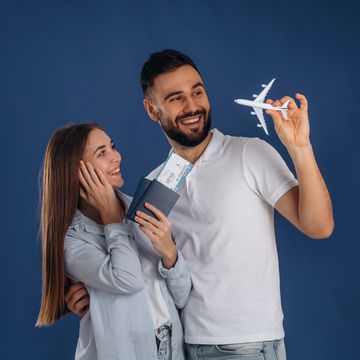 Happy couple holding passports and airplane model, excited for travel.