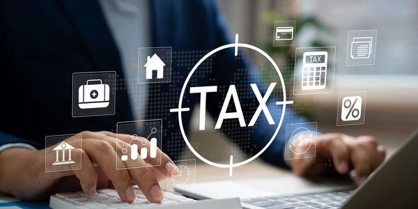Person sitting at desk working on a laptop computer and taxes.