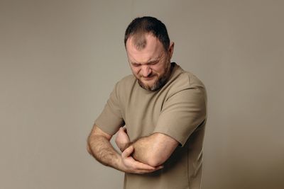 Man holding his arm, showing muscle tension treated with sports massage.