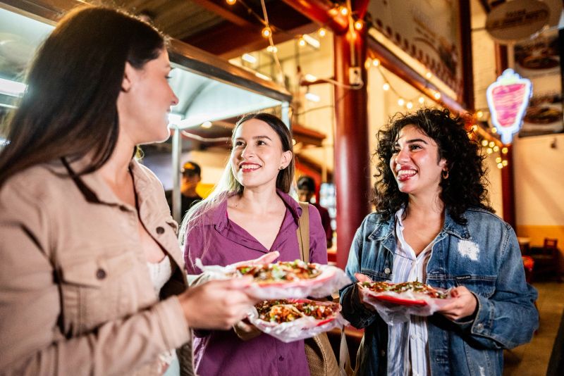 Friends women talking and eating taco outdoors