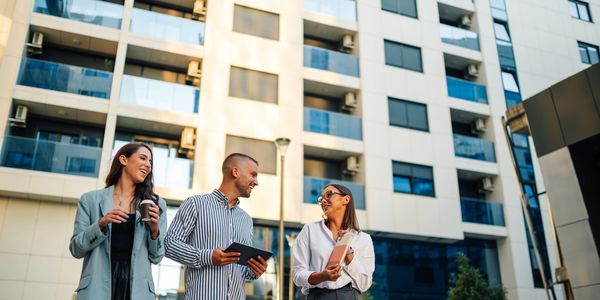 Three colleagues chatting and laughing outside a modern office building.