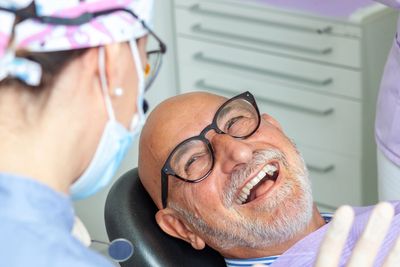 Smiling elderly man at the dentist's office, enjoying his visit.