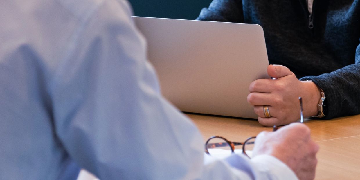 Zwei Personen bei einer Besprechung mit Laptop und Brille.