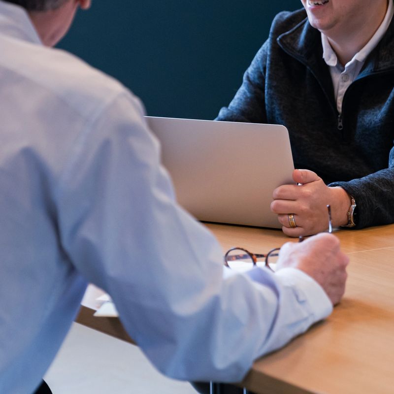 A group of 3 businessmen, one younger and two older, meet in an office to discuss ideas for project development and future success. Cropped in for close up detail shots.