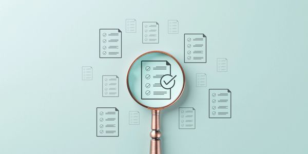Magnifying glass highlighting a checklist among multiple documents.