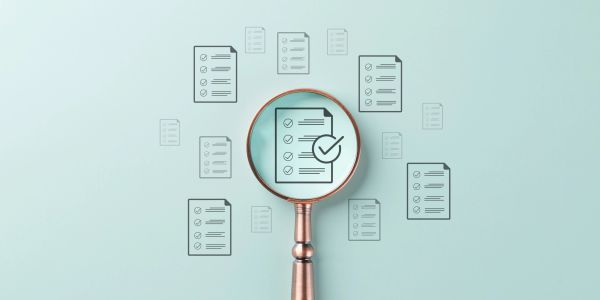 Magnifying glass focusing on a checklist among multiple documents.