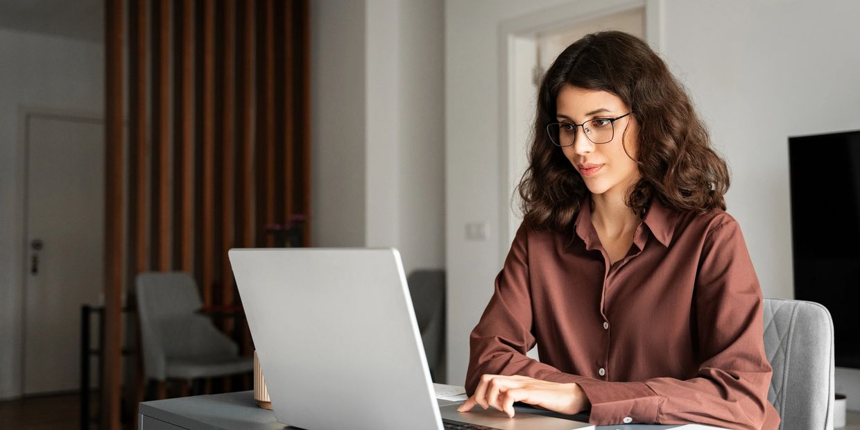Young woman working attentively on a laptop in a modern office.