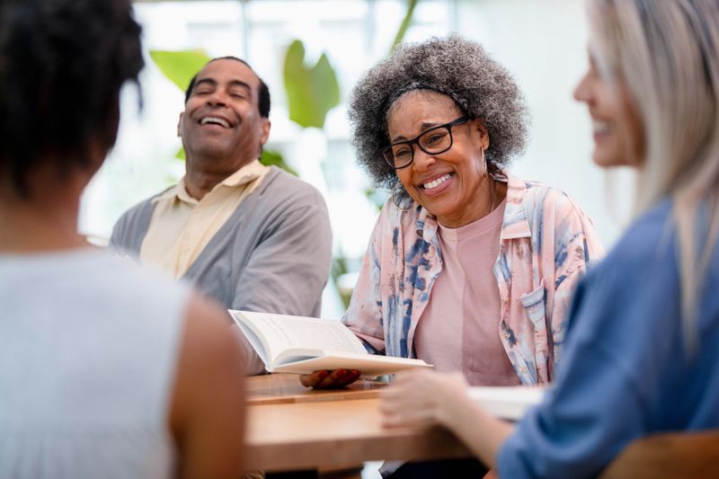 Smiling adults in casual clothes enjoy a lively book club discussion.