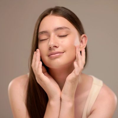 Young woman enjoying skincare with closed eyes.