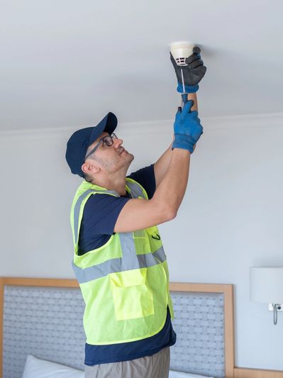 Electrician installing ceiling smoke detector.
