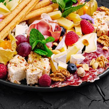 Variety of cheeses, meats, fruits, and nuts on a platter.