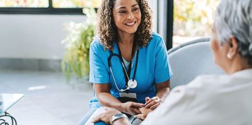 A smiling male nurse consulting with a female patient in a cozy home setting.