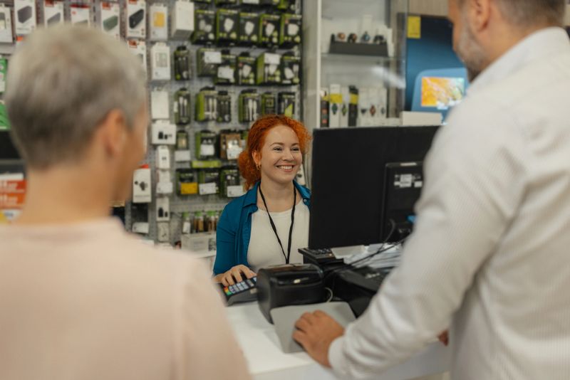 Two satisfied shoppers smile as they finalize their purchase at the register, showing excitement and appreciation for the friendly service provided by the attentive cashier.