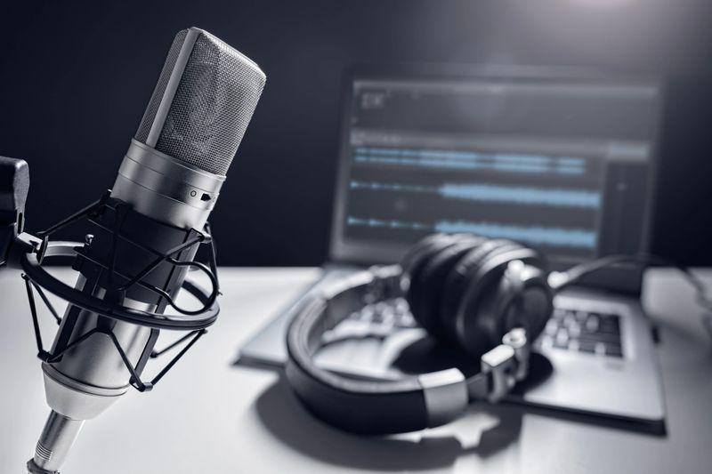 Podcast microphone, laptop computer and headphones on desk in recording studio