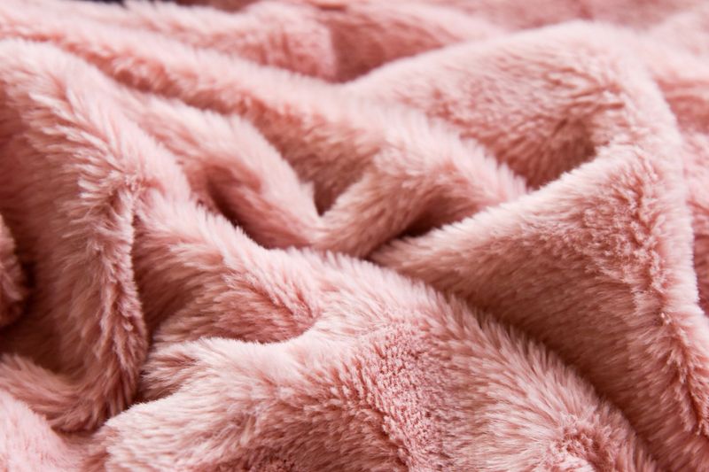 Soft, pink, fluffy fabric with folds and texture close up view.
